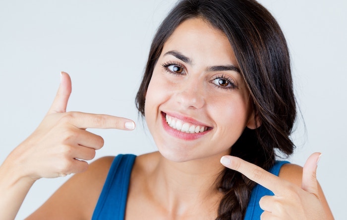 Smiling woman checks for cracked teeth symptoms.