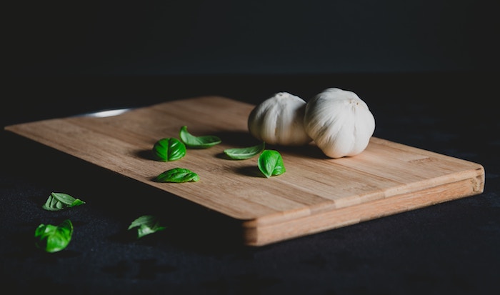 Garlic sits on a cutting board, ready to help improve your dental health.