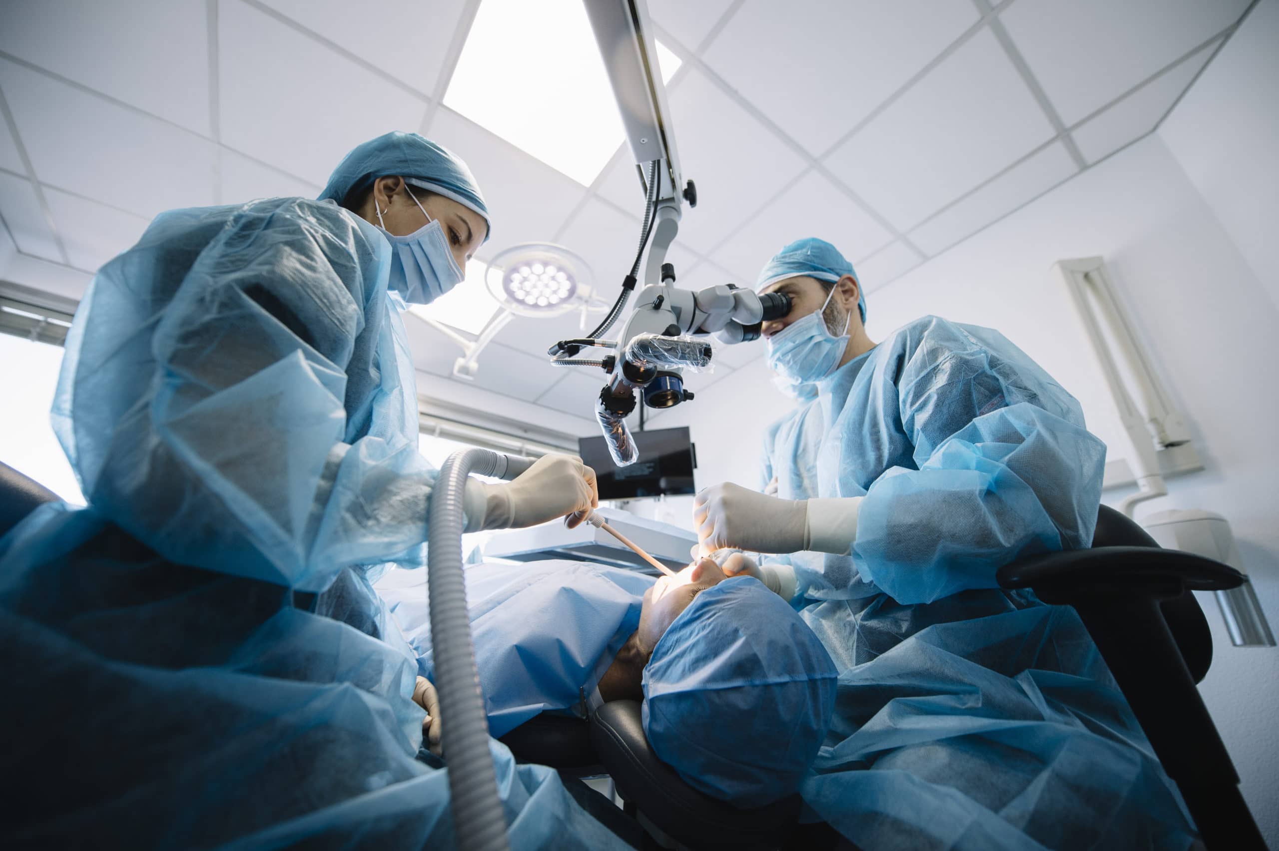 Endodontists performing a root canal under a surgical microscope