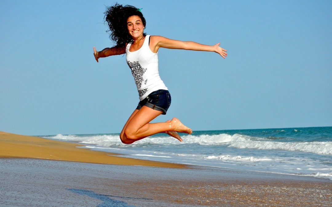 Girl with health smile jumping at the beach.