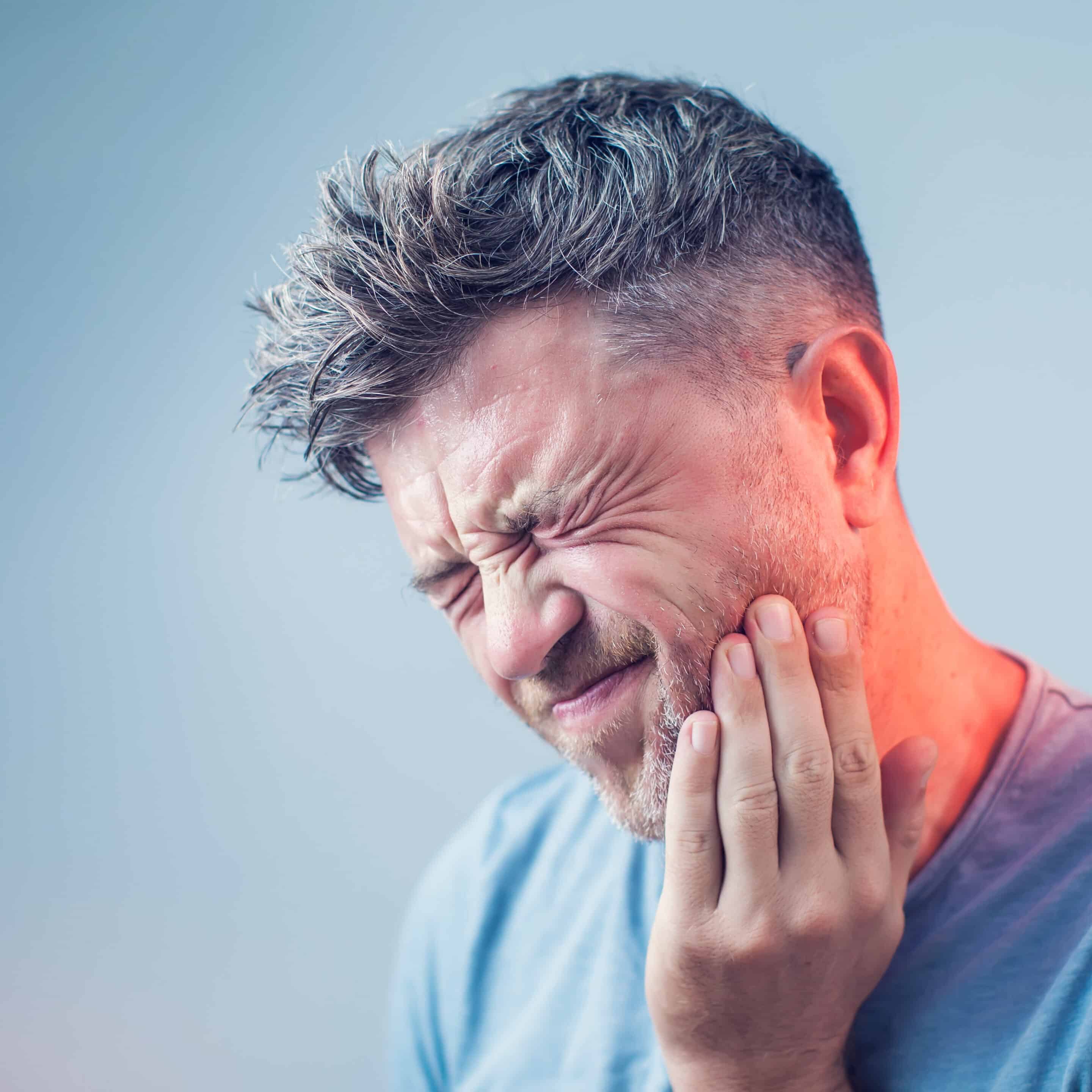 Patient holding jaw in tooth pain